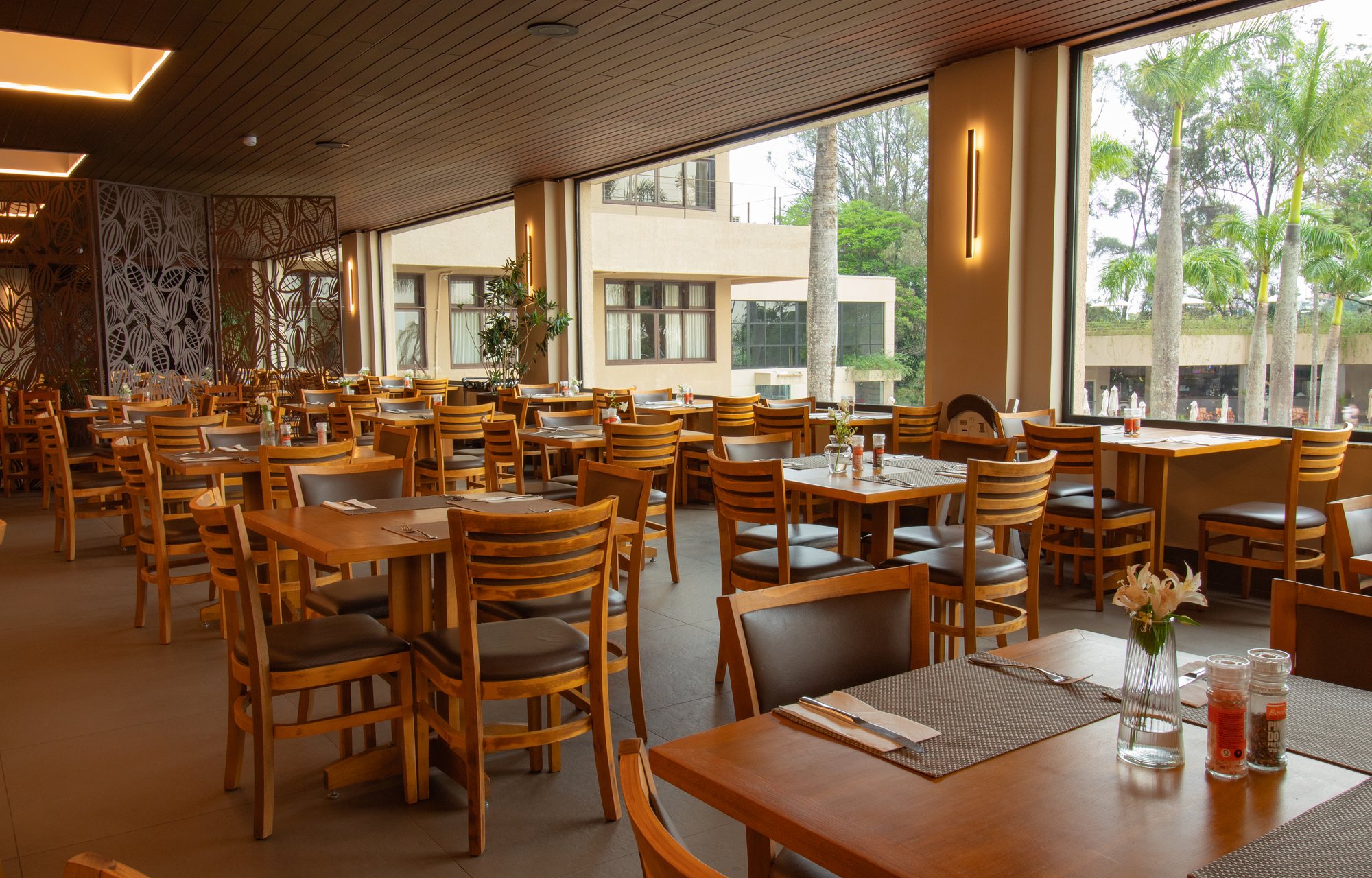 Salão do restaurante Bendito Cacao com vidros fixos panorâmicos e vista para o jardim
