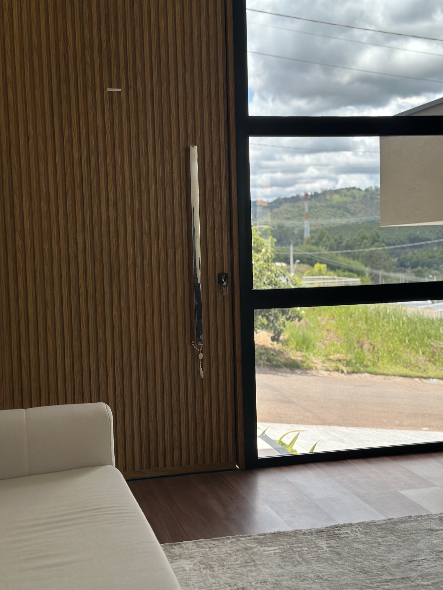 Vista interna da porta principal pivotante ripada amadeirada com pele de vidro lateral
