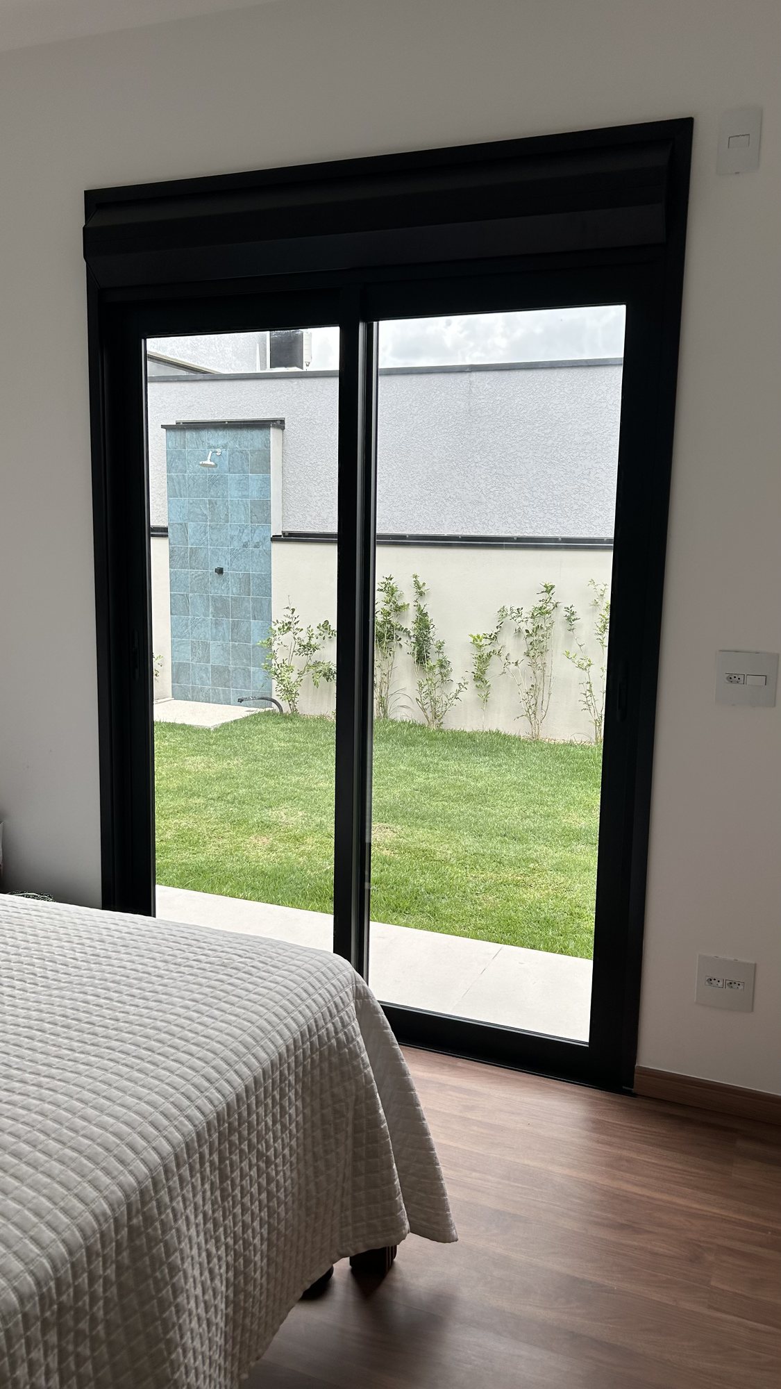 Porta de correr de alumínio preto com vista para o jardim da casa em Bragança Paulista