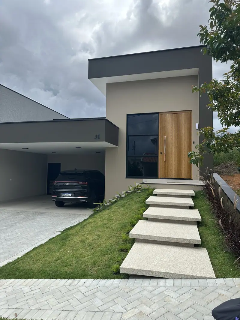 Fachada de casa de alto padrão em Bragança Paulista com porta pivotante ripada amadeirada e esquadrias pretas