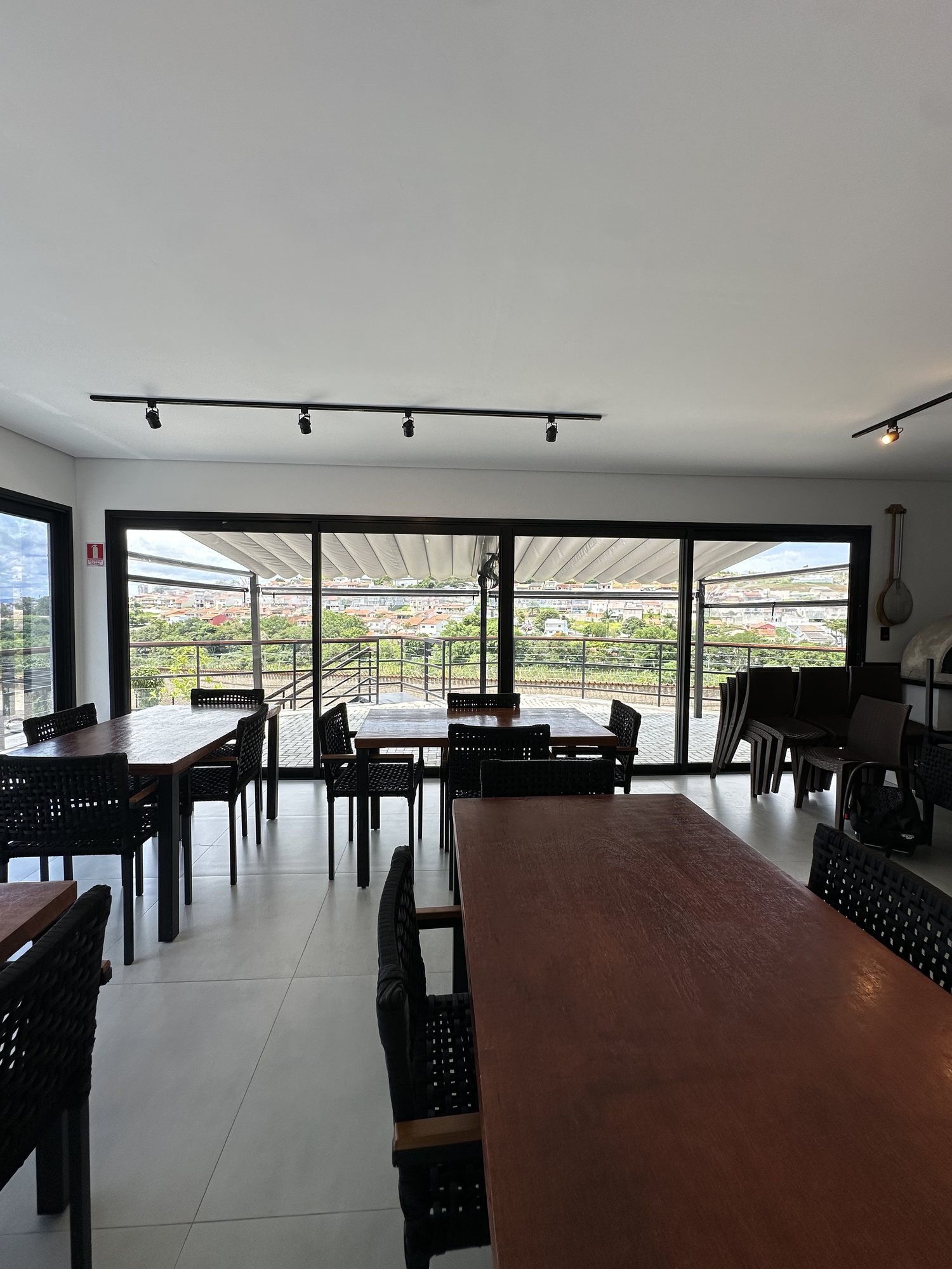 Portas de correr de alumínio preto abertas para o terraço da churrascaria em Bragança Paulista