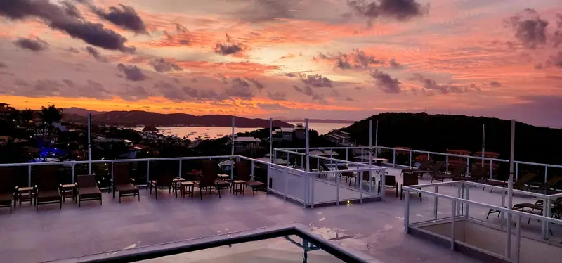 Guarda-corpo de vidro da Pousada Santorini em Búzios/RJ com vista para o mar ao pôr do sol